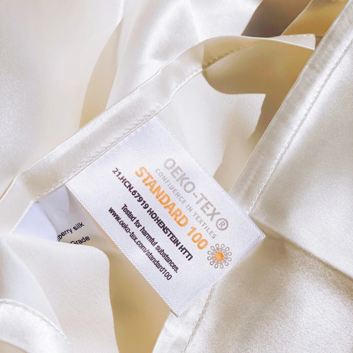 Gros plan sur l'étiquette OEKO-TEX Standard 100 cousue sur une taie d'oreiller en soie ivoire Scrunch'it Silk.