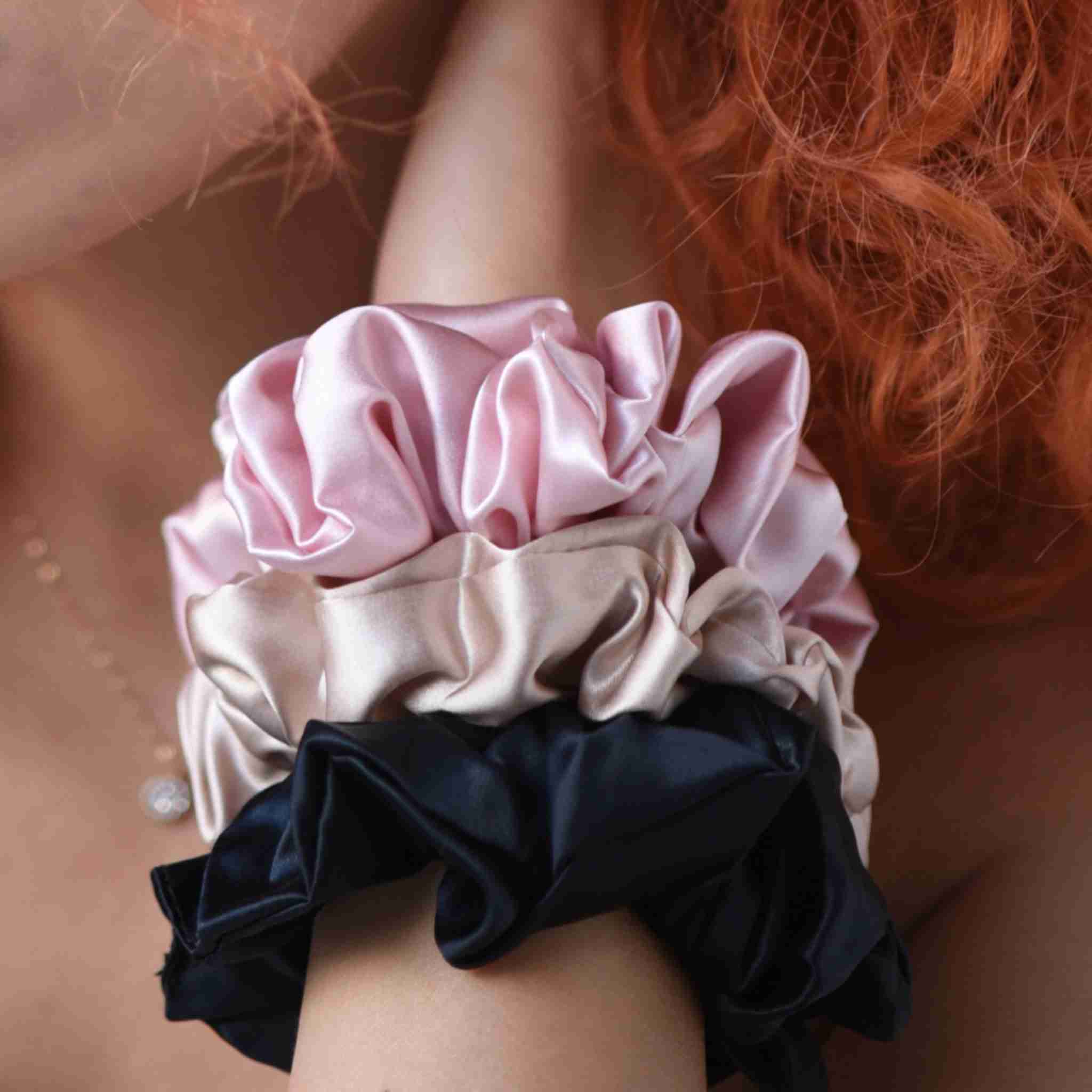 Accessoires cheveux chouchous en soie de mûrier de taille large, de couleur noir, beige et rose. Pack de trois élastiques en soie pure pour protéger les cheveux de la casse et attacher les cheveux sans les abîmer et sans laisser de trace. Accessoire chic et romantique pour les coiffures pour femme.