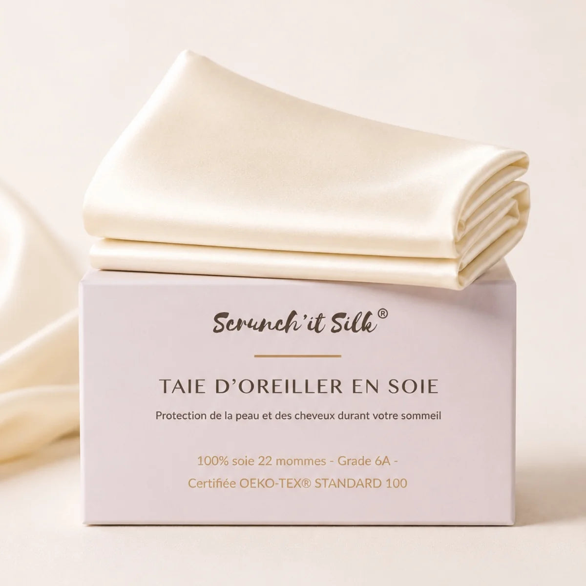 taie d'oreiller en soie ivoire 22 mommes scrunch'it silk, pliée sur sa boite de présentation.